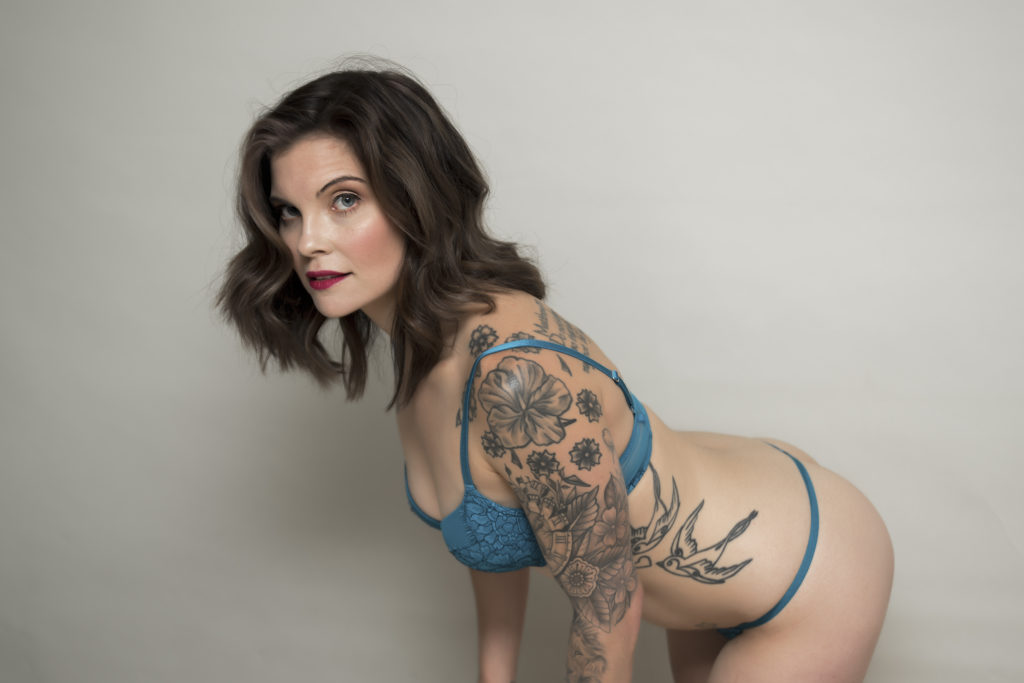 boudoir image of woman in blue lingerie on white backdrop with tattoos